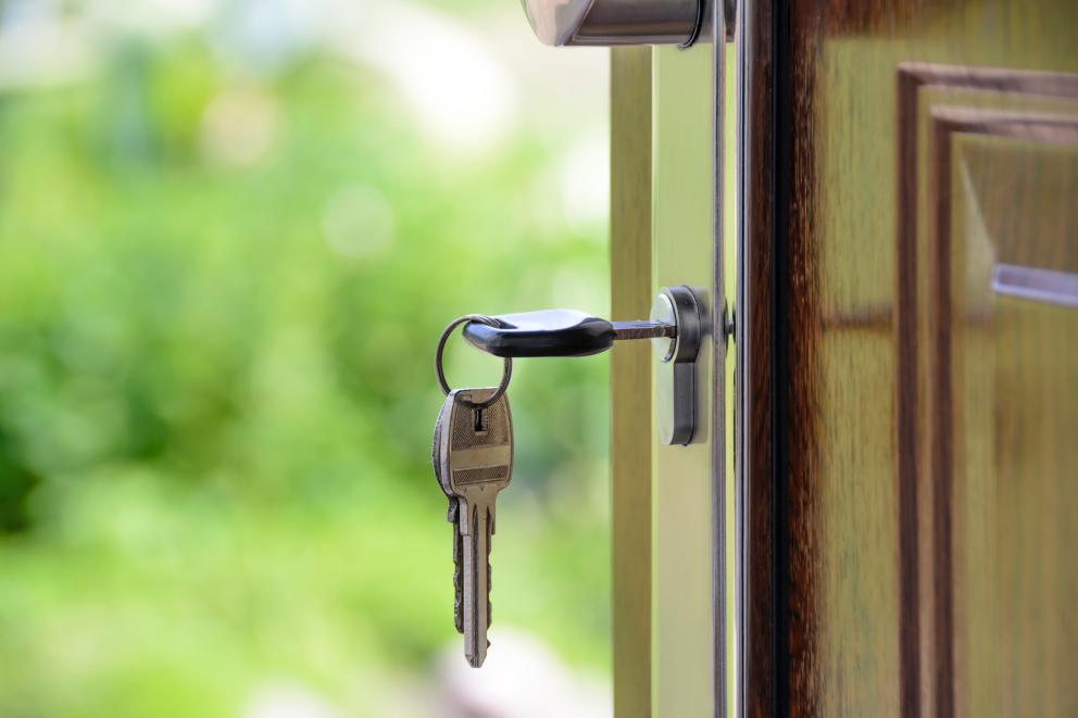 Image shows a front door open with a key in the lock