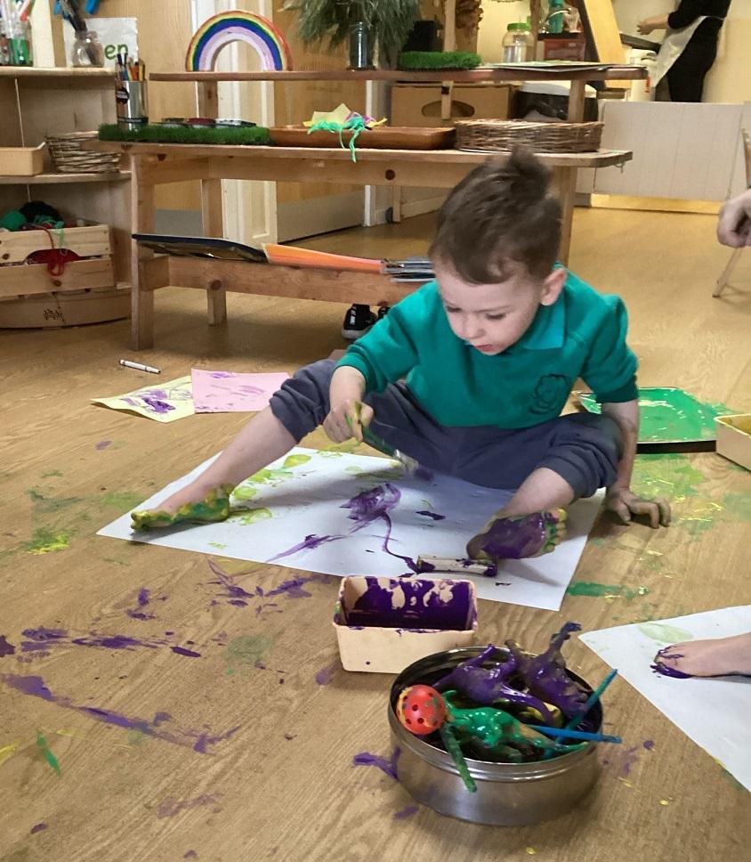 Pre-five boy playing with paint and paper. He has bare feet