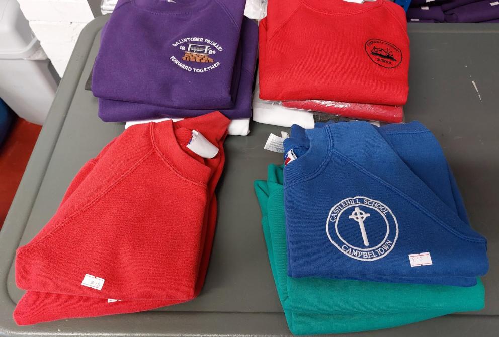 Images shows folded  red and blue school jumpers