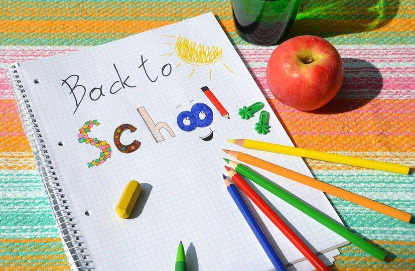 Images shows a notebook with the words back to school with four colour pencils pointing to the words