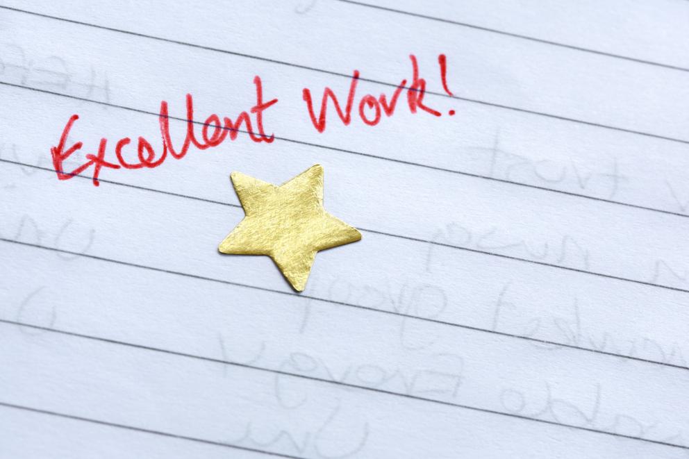 Images shows a gold star on notepaper with the words excellent work