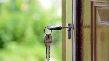 Image shows a front door open with a key in the lock