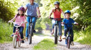 Images shows two adults and two children cycling down a track