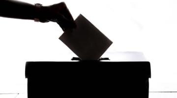 hand putting vote into a ballot box