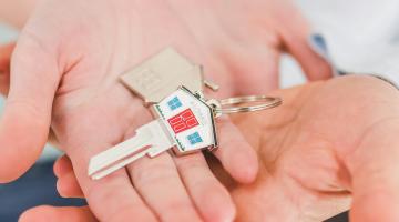 two sets of hands cradling a key with a house shaped keyring