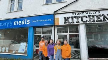 Four people standing outside the shop