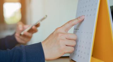 Images shows a calendar with a finger pointing to a date 