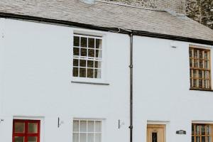 Image shows two white terrace houses next to each other. The house on the left has a red door with two windows above each other. 