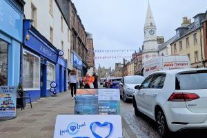 Images shows Campbeltown High Street shops to the left of the picture. Bunting flies above the street and in the foreground is the Argyll and Bute gift card