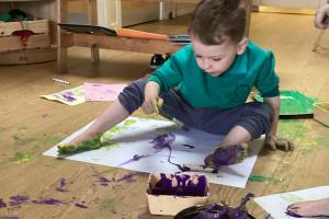 Pre-five boy playing with paint and paper. He has bare feet