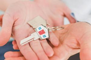 two sets of hands cradling a key with a house shaped keyring