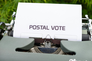 a typewriter with paper in it with the words postal vote