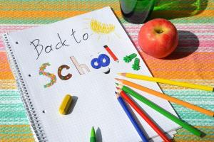 Images shows a notebook with the words back to school with four colour pencils pointing to the words